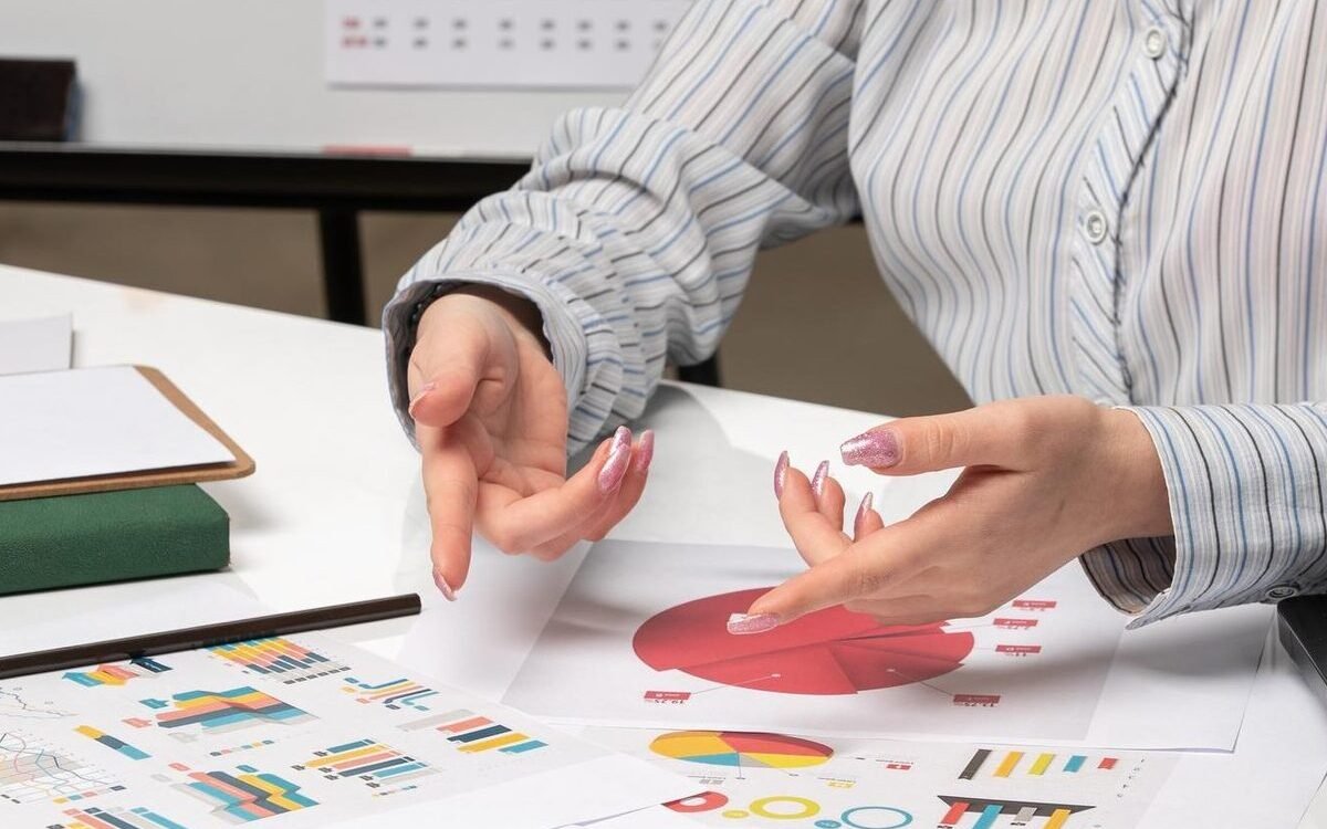 photo des mains d'une personne qui explique quelques choses avec des diagramme sur la table